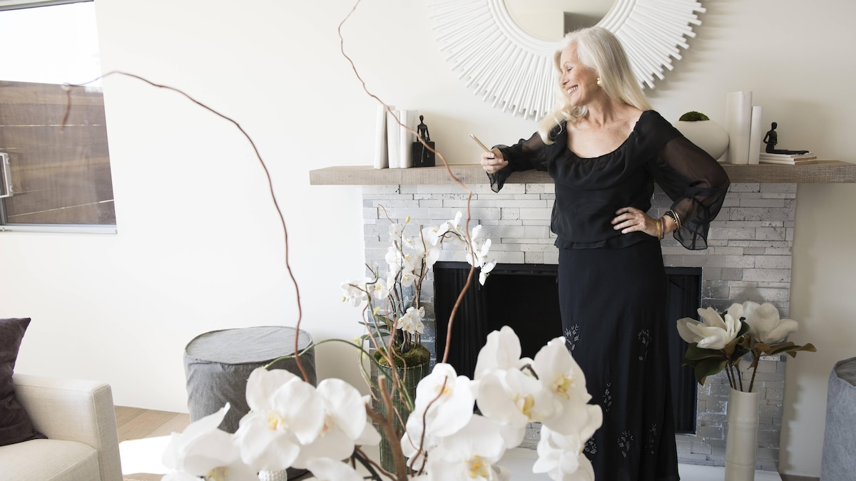 Senior woman standing in stylish living room, looking at her phone, 13.02.2015, Copyright: xDavidxJaklex, model released, wearing,holding,looking,using,black color,gray hair,at home,real people,style,elegance,glamour,success,text message,happiness,orchid,60 to 64 years,caucasian ethnicity,female,woman,senior woman,only one senior woman,one person,house interior,fireplace,mantelpiece,indoors,living room,dress,communication,hands on hips,smiling,standing,modern,long hair,smartphone,fulfillment,February 2015 R